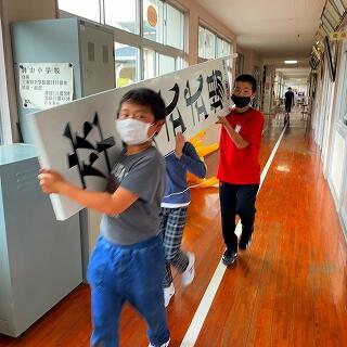 看板は３人で運びます