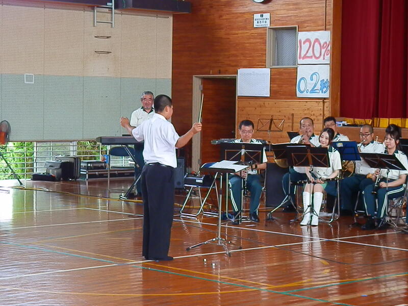 生徒代表が楽団を前に指揮をする様子