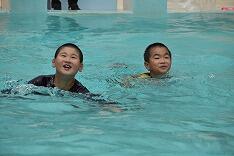 服を着たまま泳ぐ児童