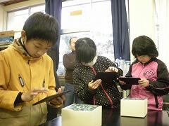 タブレットをテキストにかざす児童