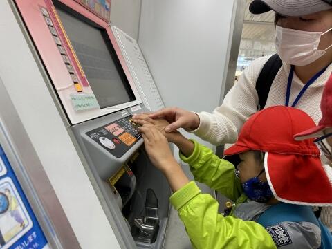 券売機の音声や点字に従って切符を買う様子